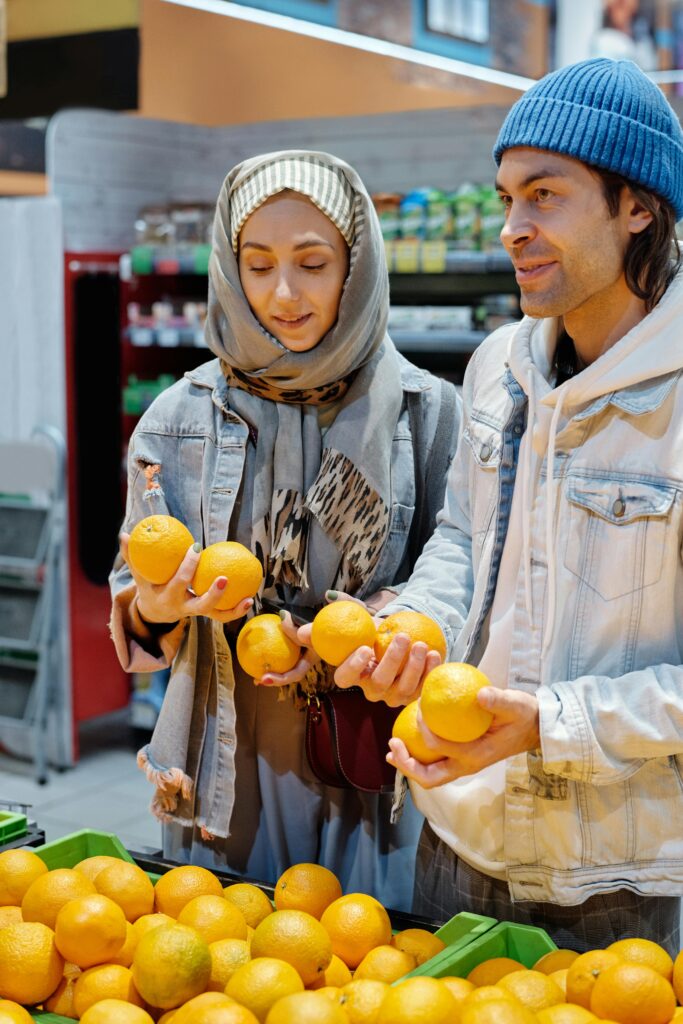 pexels-photo-4199140-4199140 Man and woman selecting oranges in a supermarket, focused on quality and freshness.
